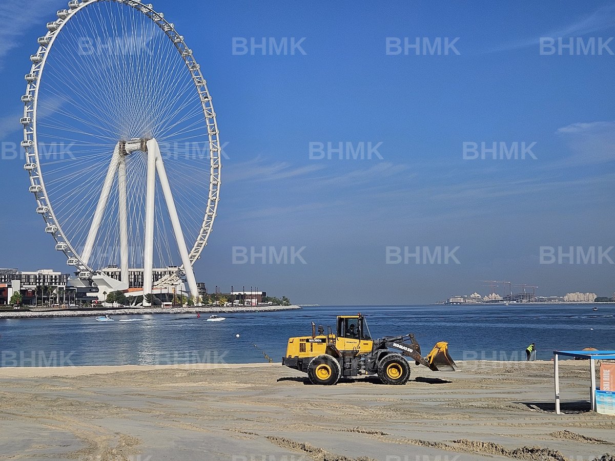 BHMK CAT wheel loader profiling a Dubai beach with the Marina skyline behind