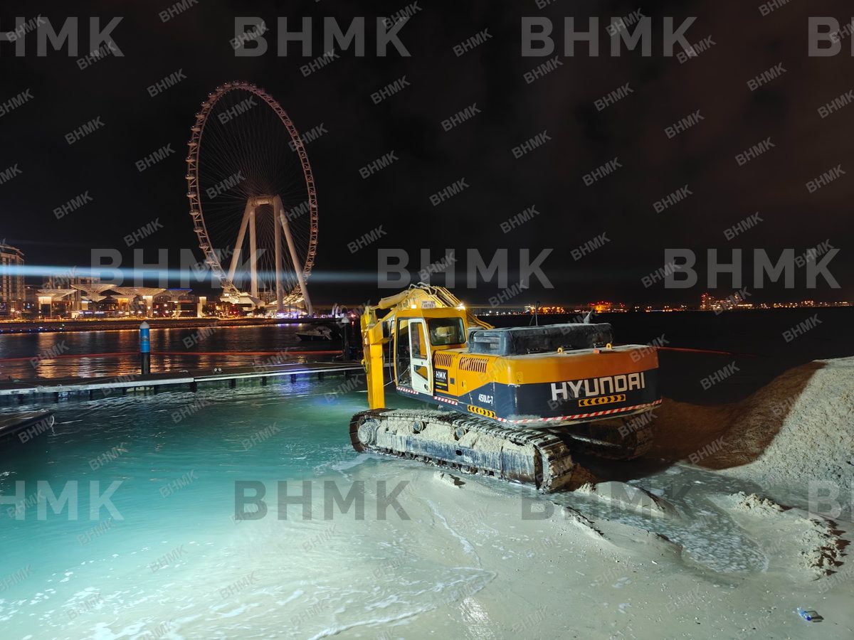 BHMK excavator working on beach nourishment at night, Dubai