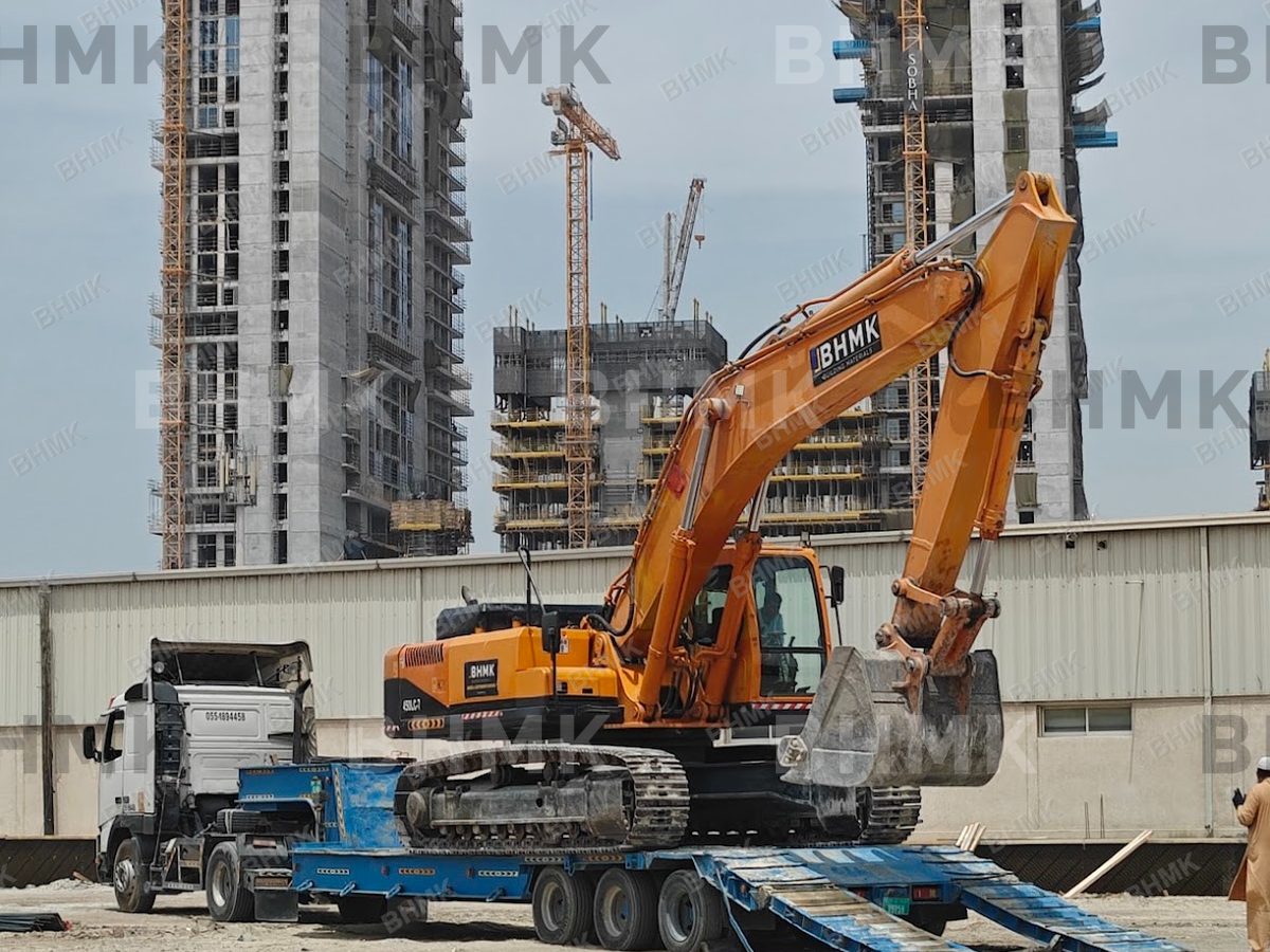 BHMK branded excavator on site with Dubai skyline